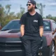 Bearded man in sunglasses leaning on red sports car