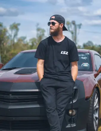 Bearded man in sunglasses leaning on red sports car