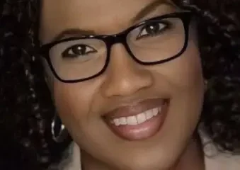 Smiling woman with curly hair and glasses