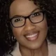 Smiling woman with curly hair and glasses