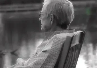 Elderly person sitting by lakeside in chair