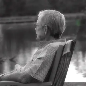 Elderly person sitting by lakeside in chair