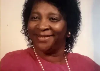 Smiling woman in pink blouse with pearl necklace