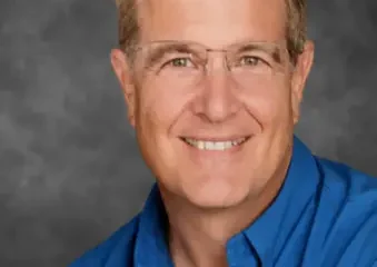 Smiling middle-aged man in blue shirt and glasses