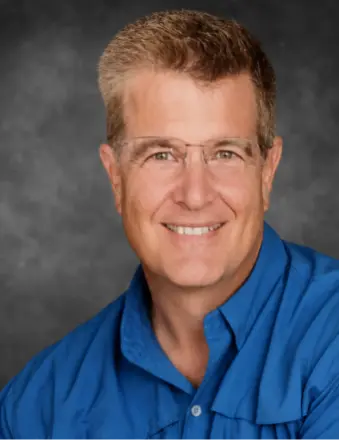 Smiling middle-aged man in blue shirt and glasses