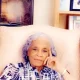 Elderly woman sitting thoughtfully in armchair