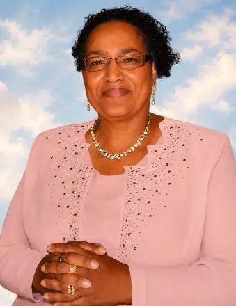 Woman in pink suit smiling against sky backdrop