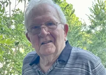 Elderly man with glasses standing outdoors