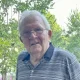 Elderly man with glasses standing outdoors