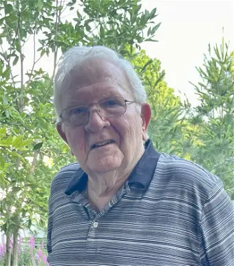 Elderly man with glasses standing outdoors
