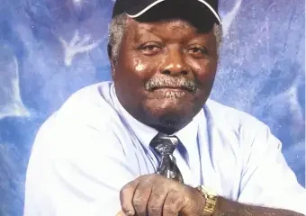 Older man in cap posing against blue backdrop