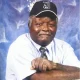 Older man in cap posing against blue backdrop