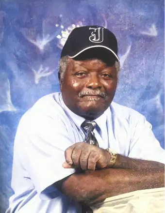 Older man in cap posing against blue backdrop