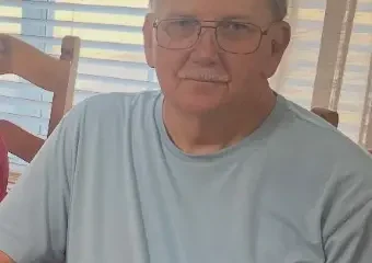 Older man with glasses sitting indoors by window