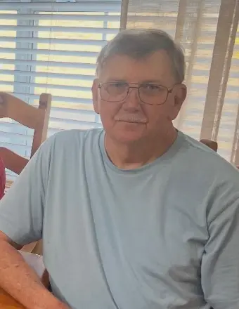Older man with glasses sitting indoors by window