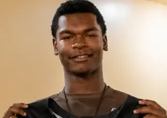 Young man holding black sports jersey indoors