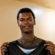 Young man holding black sports jersey indoors