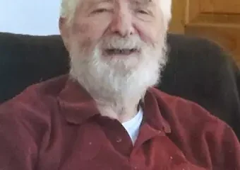 Elderly man with white beard smiling indoors