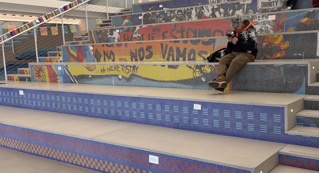 Man sitting on colorful mosaic bleachers indoors