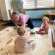 Caregiver playing with two toddlers on mat