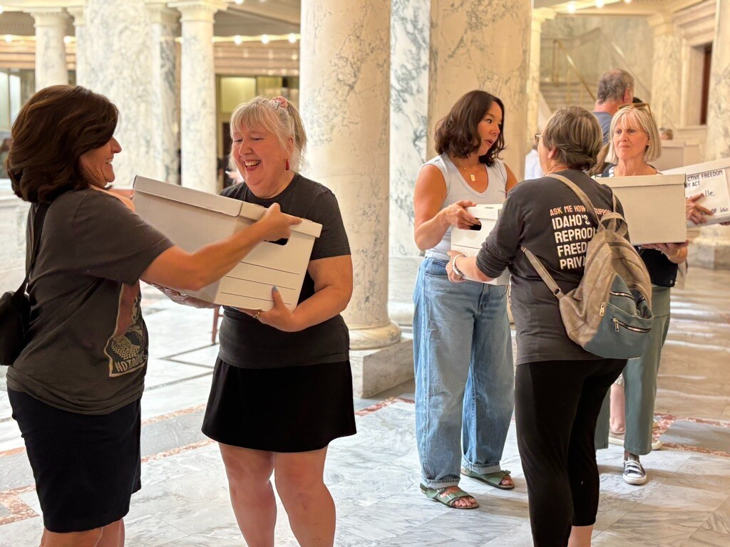 Women carrying document boxes inside marble capitol building