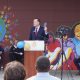 Man speaking at podium before colorful mural