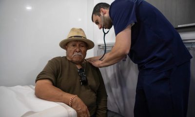 Doctor examining elderly man with stethoscope