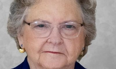 Elderly woman wearing glasses and gold brooch
