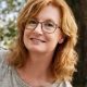 Smiling red-haired woman with glasses outdoors
