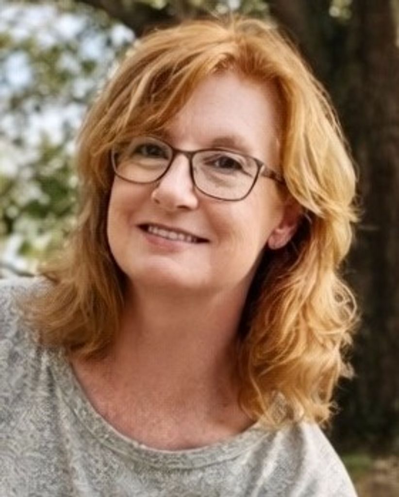Smiling red-haired woman with glasses outdoors