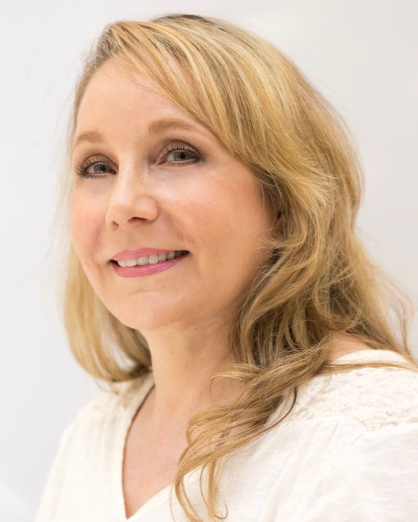 Smiling middle-aged blonde woman against light background