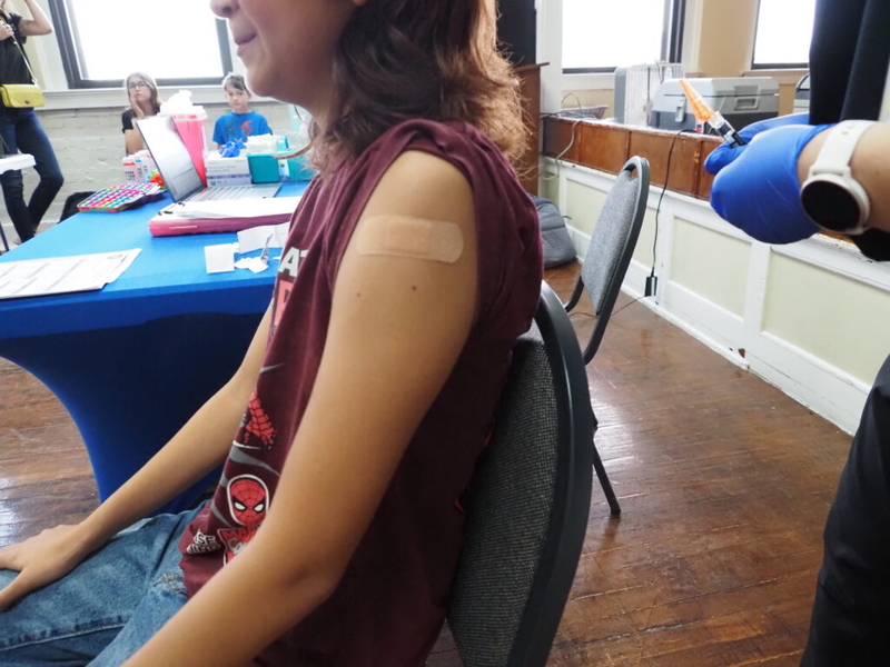 Child receiving vaccination with bandage on arm