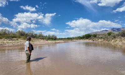 Man standing in shallow muddy river landscape