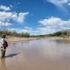 Man standing in shallow muddy river landscape