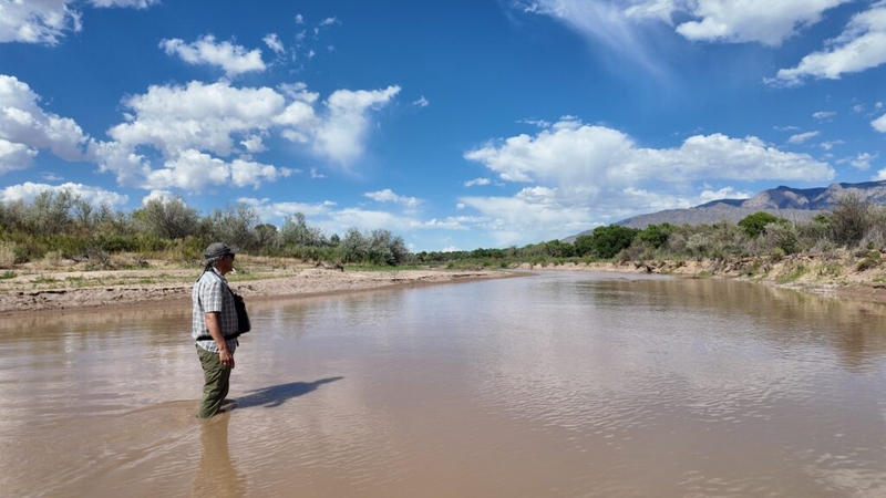 Man standing in shallow muddy river landscape