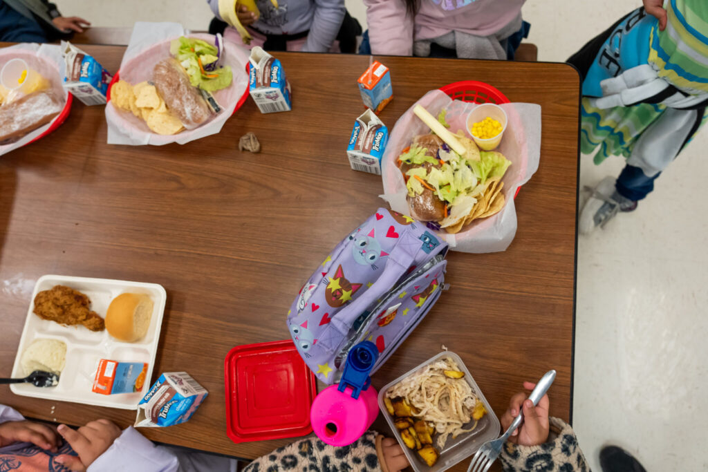 Children eating school lunch at cafeteria table