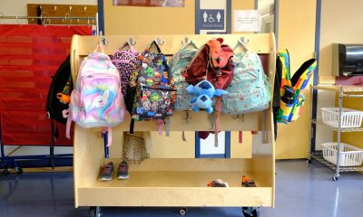 Colorful children's backpacks hanging on classroom rack