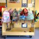Colorful children's backpacks hanging on classroom rack