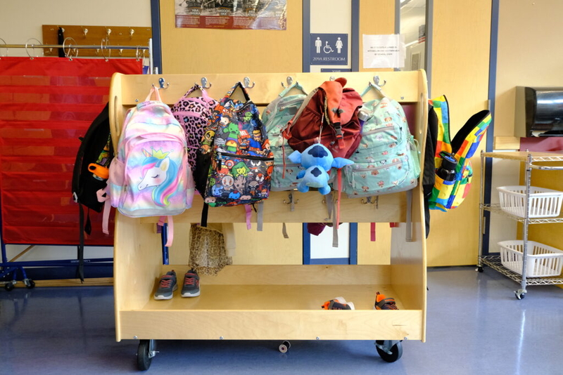 Colorful children's backpacks hanging on classroom rack