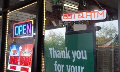 Storefront window with neon OPEN and lottery signs