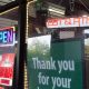 Storefront window with neon OPEN and lottery signs