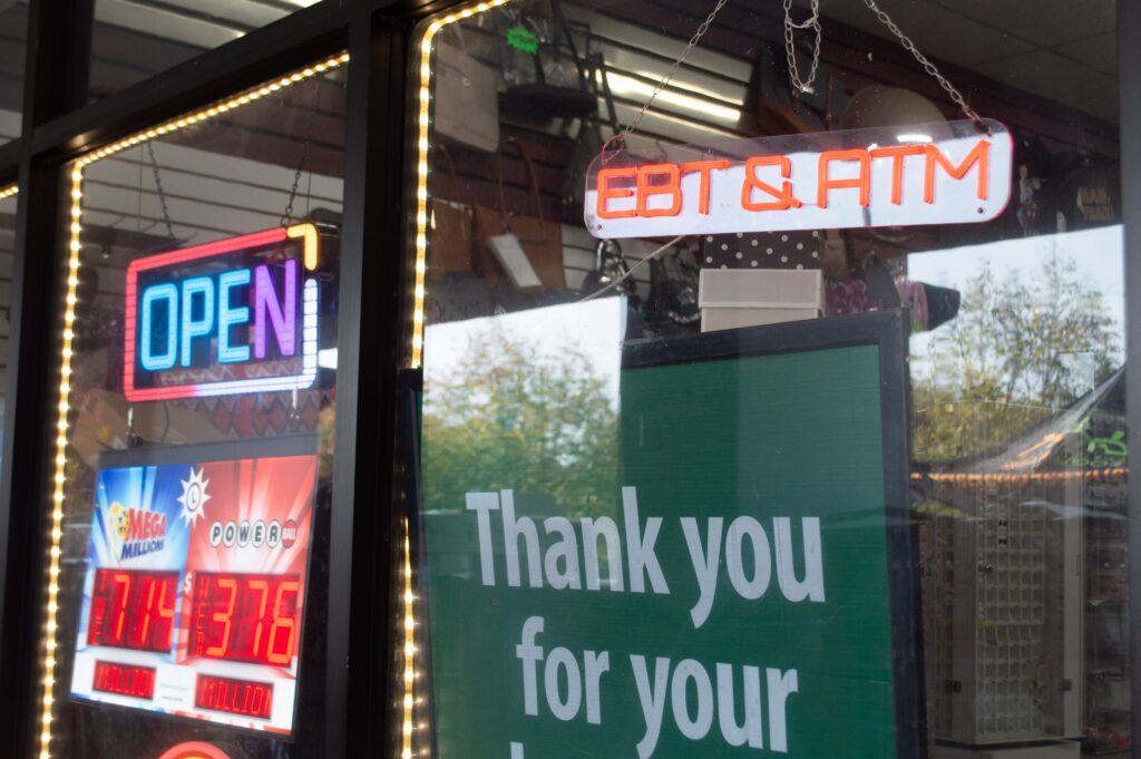 Storefront window with neon OPEN and lottery signs