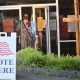 Voters entering polling place with Vote Here sign