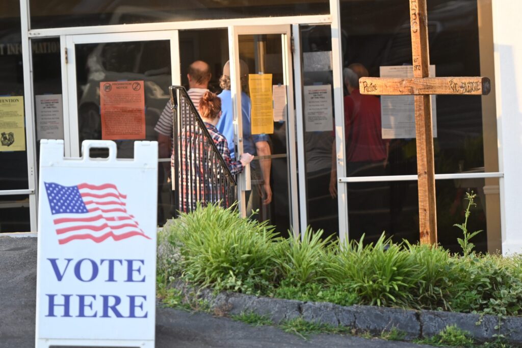 Voters entering polling place with Vote Here sign