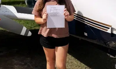 Woman holding document in front of small airplane