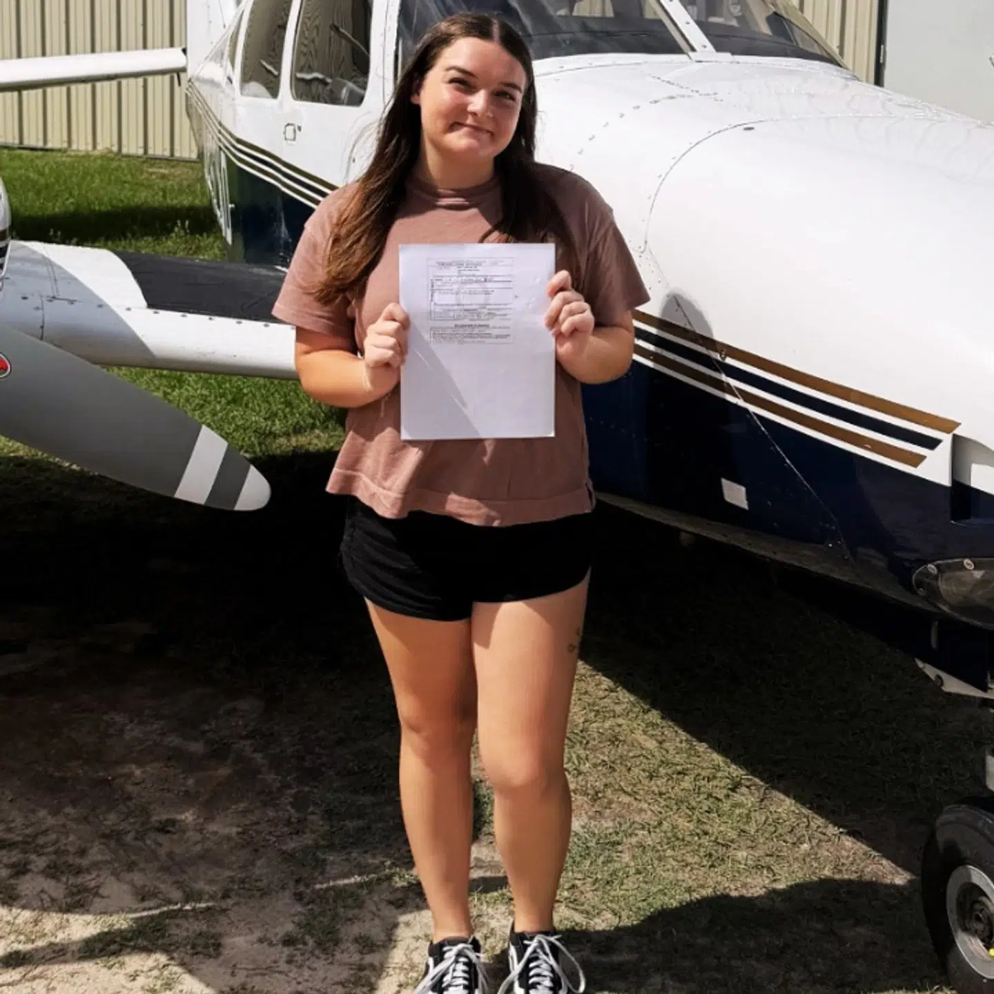 Woman holding document in front of small airplane