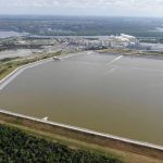 Aerial view of a large phosphogypsum stack in Florida, surrounded by water and greenery. — florida phosphogypsum road test
