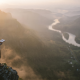Man reading on cliff above winding river valley