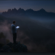 Person reading on cliff at dusk mountains