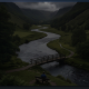 Winding river through green valley with small bridge